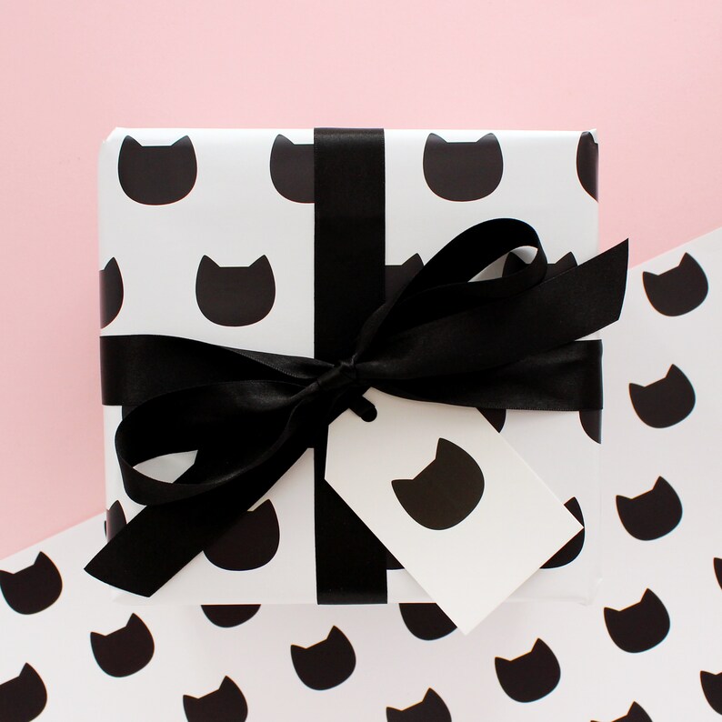 Gift wrapped in monochrome cat wrapping paper with a black ribbon bow and matching cat gift tag attached.