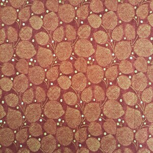 Peut inclure: Tissu rouge avec un motif répétitif de feuilles dorées et de points blancs.
