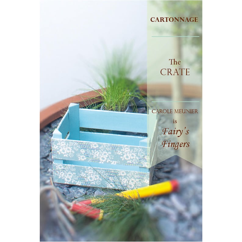 May include: A blue wooden crate with a white floral pattern. The crate is sitting on a gray stone surface. The text 'CARTONNAGE', 'The CRATE', 'CAROLE MEUNIER is Fairy's Fingers' is visible on the image.