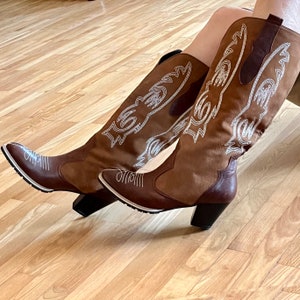 Women&#39;s high leather cowboy boots,  red color with light beige embroidery, the sole is made by hand with a welt, the heel is 7 cm high.