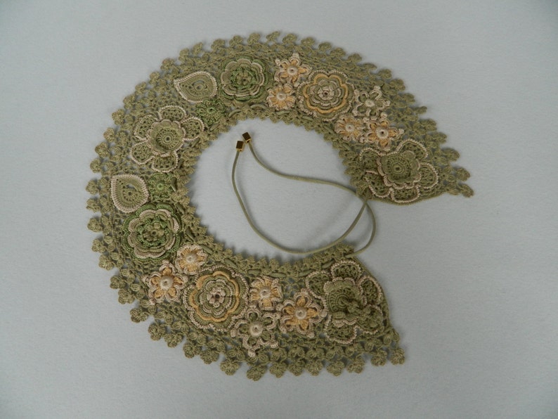 May include: A green crocheted collar with delicate floral designs and a brown leather cord.