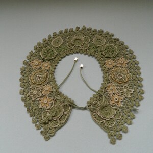 May include: A green crocheted collar with delicate floral designs and a tie closure.
