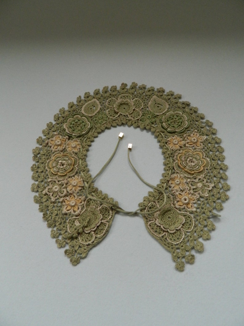 May include: A green crocheted collar with delicate floral designs and a tie closure.