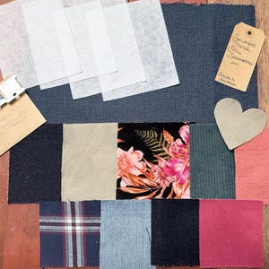 May include: A collection of fabric swatches in various colors and textures, including a floral print, corduroy, and plaid. The image also includes a heart-shaped cutout, thread spools, and a tag with handwritten text.