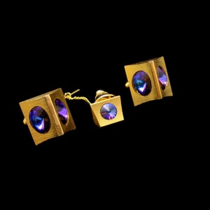 May include: A set of three gold-toned cufflinks and a tie tack with iridescent blue and purple stones.