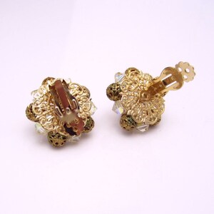 May include: A pair of gold tone clip-on earrings with clear iridescent crystals and green beads.