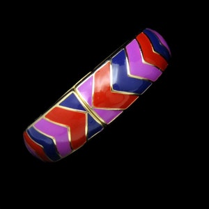 May include: A gold bangle bracelet with a geometric pattern of red, purple and blue enamel.