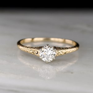 Antique Late Victorian (c. 1890s - 1900s) Petite Gold Solitaire with Ornamented Shoulders and an Early Transitional / European Cut Diamond