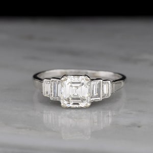 Vintage Art Deco Engagement Ring with Stepped Shoulders, Featuring a Natural Emerald Cut and Baguette Cut Diamonds