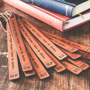May include: A set of ten brown leather bookmarks with the text "I trust the next chapter because I know the Author."  The bookmarks are arranged in a fan shape on a wooden surface.