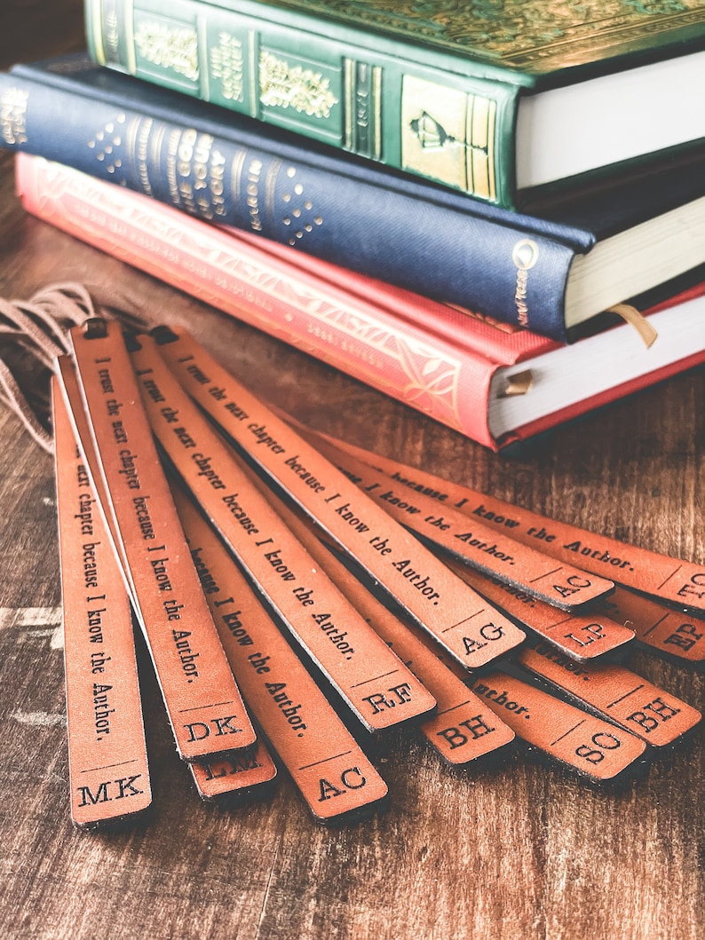 May include: A set of ten brown leather bookmarks with the text "I trust the next chapter because I know the Author."  The bookmarks are arranged in a fan shape on a wooden surface.