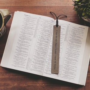May include: A brown leather bookmark with the text "I trust the next chapter because I know the Author." The bookmark is placed in an open Bible.