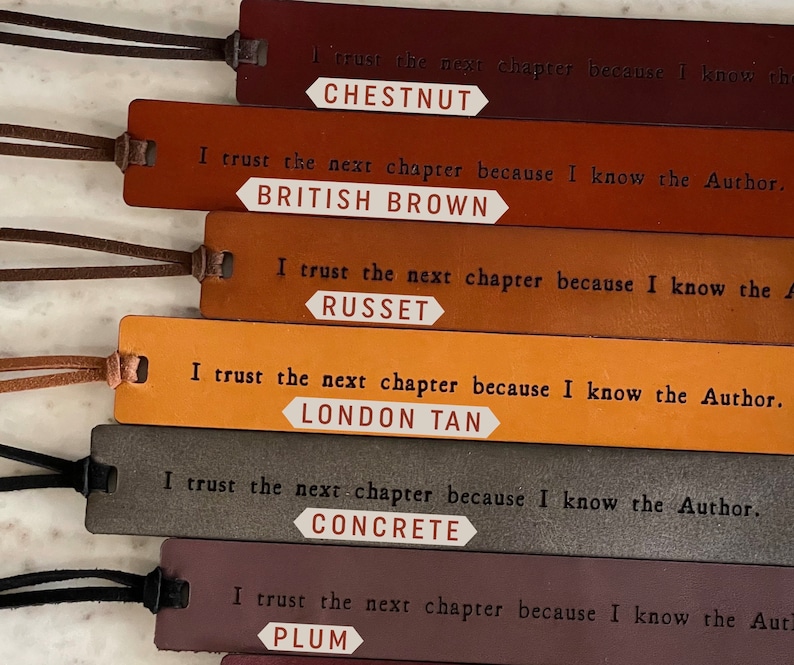 May include: Six leather bookmarks with different colors and the text "I trust the next chapter because I know the Author." and the color name of the bookmark below the text. The colors are Chestnut, British Brown, Russet, London Tan, Concrete, and Plum.