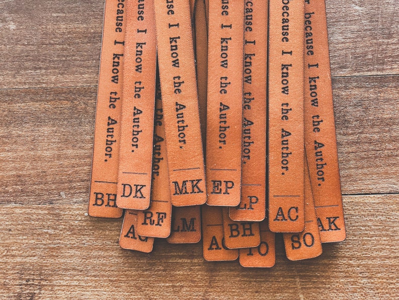May include: A set of brown leather bookmarks with the text "because I know the Author." printed on each one. The bookmarks are stacked on top of each other and have different initials on the bottom.