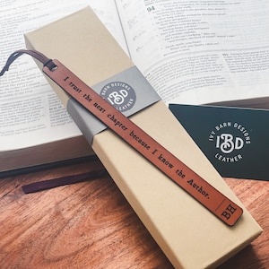 May include: A brown leather bookmark with the text "I trust the next chapter because I know the Author." and the initials "BH" engraved on it. The bookmark is packaged in a box with the logo "Ivy Barn Designs" and the text "Leather".