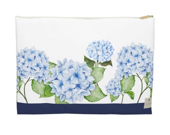 May include: White zippered pouch featuring a watercolor design of blue hydrangea flowers and green leaves. A navy blue stripe accents the bottom. The pouch has a gold-colored zipper.