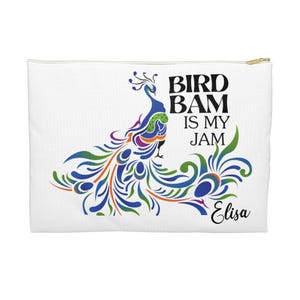 Può includere: Pochette cosmetica bianca con un design colorato di pavone. Il testo "BIRD BAM IS MY JAM" e il nome "Elisa" sono stampati. La pochette ha una cerniera dorata.