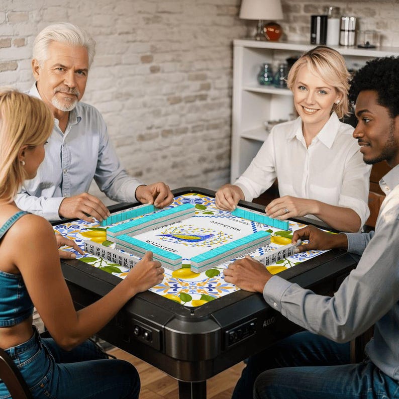 May include: A group of four people playing mahjong around a black table. The table has a colorful tile design with lemons and blue accents. The mahjong tiles are light blue and white. The game is set up and ready to play.