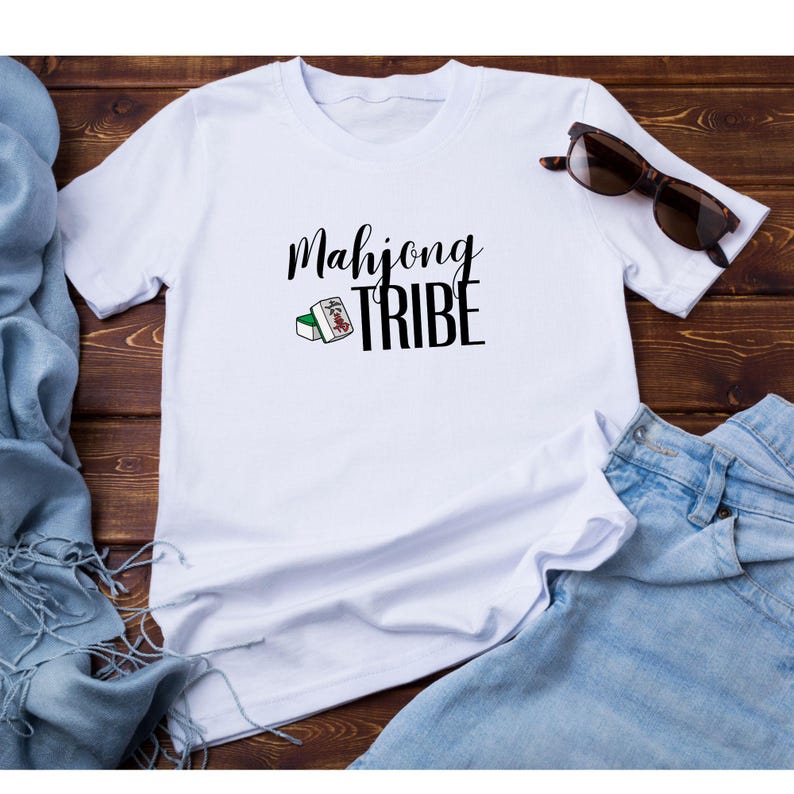 Puede incluir: Camiseta blanca con texto negro que dice "Mahjong Tribe" y una peque&ntilde;a imagen de una ficha de mahjong.