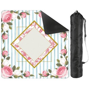 May include: A floral picnic blanket with a blue and white striped background, adorned with pink and white roses. The blanket features a gold diamond-shaped frame with a blank center. A black carrying bag is included.