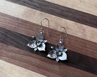 May include: A pair of silver flower earrings with a yellow gemstone in the center of each flower.