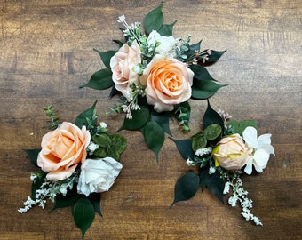 May include: Three peach and white floral arrangements with greenery, perfect for weddings or special events.