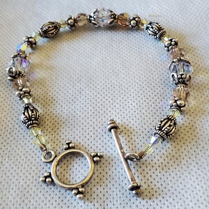 Clear Crystal Bracelet . Has Clear Crystal facted beads with Silver Caps and Silver Beads with Light Amber Color Spacers Toggle Closure .