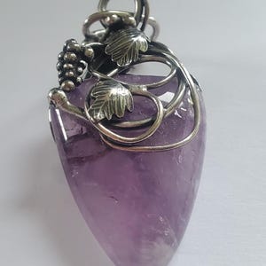 May include: A white ceramic mug with a black handle and the text "But First, Coffee" in a bold, black font. The mug is set against a blurred background, suggesting a cozy setting.