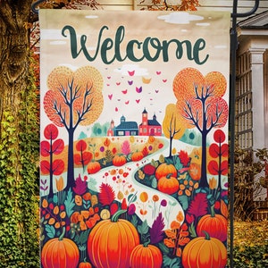 May include: A garden flag with a colorful autumn scene. The flag features a winding path, pumpkins, trees, and the word "Welcome" in green script. The background includes a house and fall foliage.