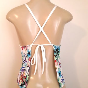 May include: White halter top with a floral print and criss-cross straps in the back.