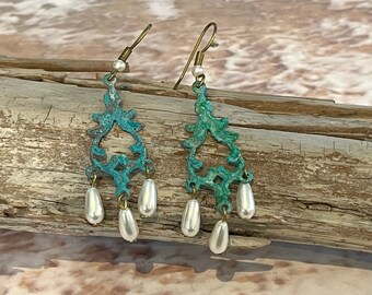 May include: A pair of dangle earrings with a turquoise blue filigree design and white pearl accents.
