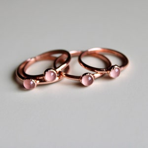 Könnte beinhalten: Drei Ringe aus Roségold mit rosafarbenen Steinen. Die Ringe sind übereinander gestapelt.