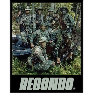 May include: A group of soldiers in camouflage uniforms and hats, holding rifles, posing in a forest setting. The word "RECONDO" is displayed in a block font at the bottom of the image.