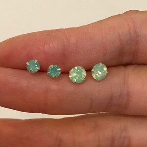 May include: Four pairs of small, round, light green opal stud earrings.