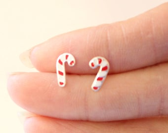 May include: A pair of silver candy cane earrings with red and white stripes.