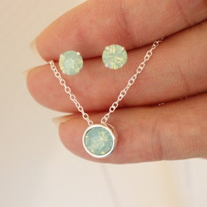 Könnte beinhalten: Ein silbernes Halsketten- und Ohrring-Set mit einem Anhänger aus hellgrünem Opal und passenden Ohrringen.