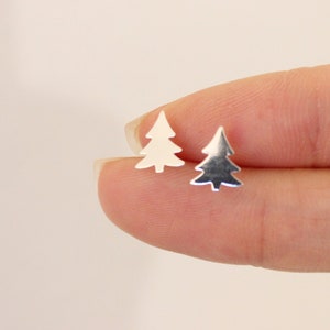 May include: A pair of silver earrings shaped like Christmas trees. The earrings are small and delicate.