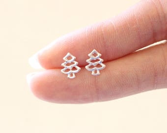 May include: A pair of silver earrings shaped like small, detailed pine trees.