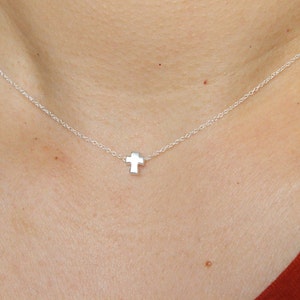 Op de afbeelding: Een zilveren ketting met een klein, zilveren kruisje als hanger.