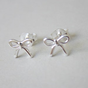 May include: A pair of silver bow-shaped stud earrings.