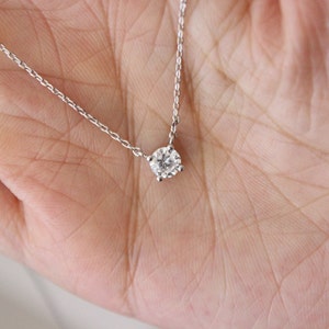 May include: A delicate silver chain necklace with a single, round, clear diamond pendant.