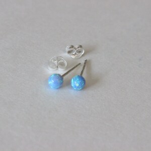 May include: A pair of silver stud earrings with light blue opal stones.