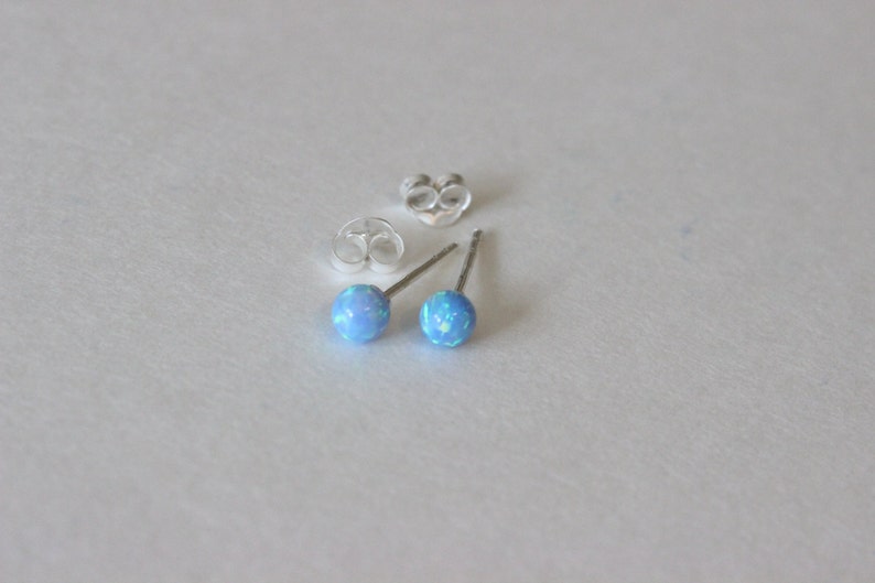 May include: A pair of silver stud earrings with light blue opal stones.