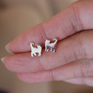 Op de afbeelding: Een paar zilveren oorbel studs met katten silhouetten.