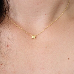 May include: A delicate gold chain necklace with a small, star-shaped pendant.
