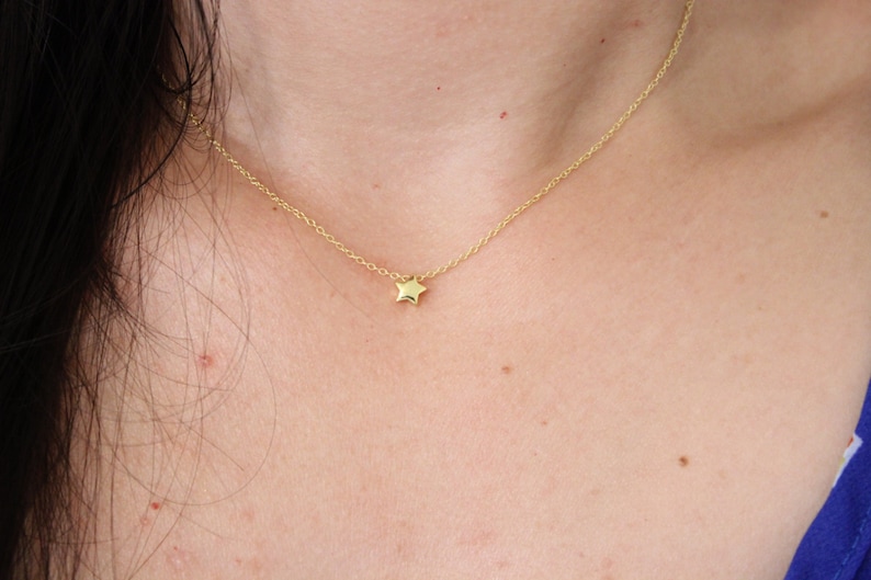 May include: A delicate gold chain necklace with a small, star-shaped pendant.