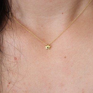 May include: A delicate gold chain necklace with a small, star-shaped pendant.