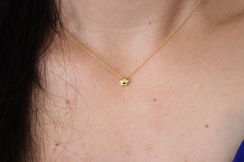 May include: A delicate gold chain necklace with a small, star-shaped pendant.