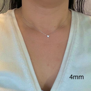 May include: A delicate silver chain necklace with a small, clear, round gemstone pendant. The pendant is 4mm in diameter.