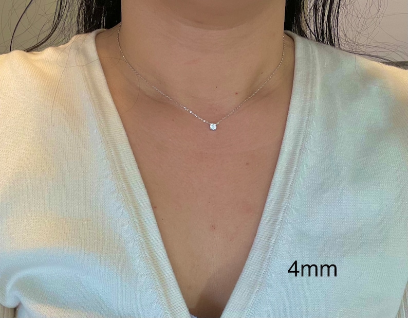 May include: A delicate silver chain necklace with a small, clear, round gemstone pendant. The pendant is 4mm in diameter.